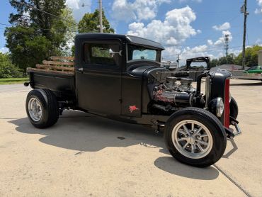 Classic black hot rod truck with wooden bed and custom wheels.