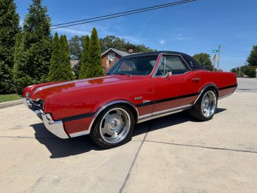 Red vintage convertible car parked outdoors.