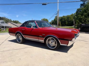 Classic red muscle car parked outdoors on a sunny day.