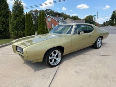 Gold classic Pontiac GTO parked on driveway.