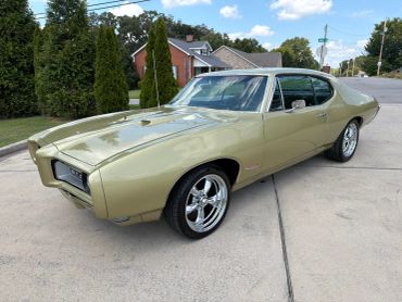 Classic beige muscle car parked on a driveway.