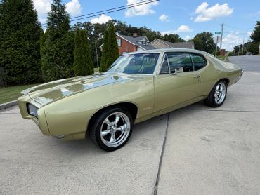 Classic gold-colored muscle car parked on driveway.