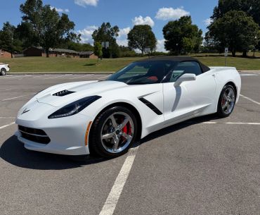 White Chevrolet Corvette convertible parked in an empty lot.