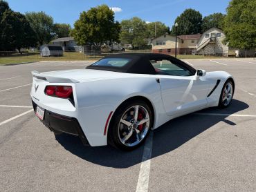 White convertible sports car parked in an empty lot.