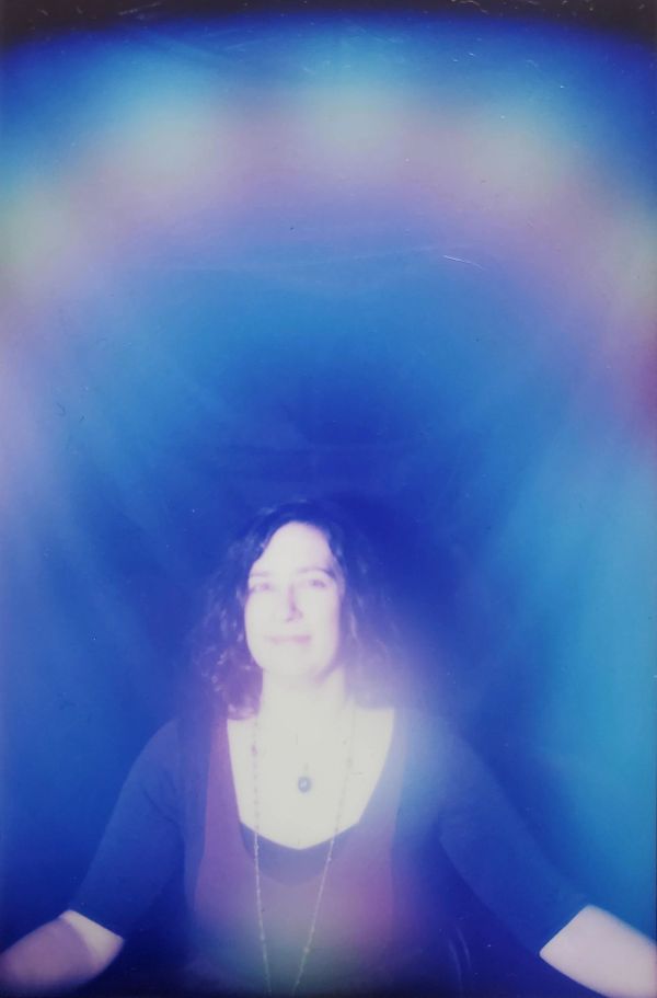 Person surrounded by colorful aura-like glow.