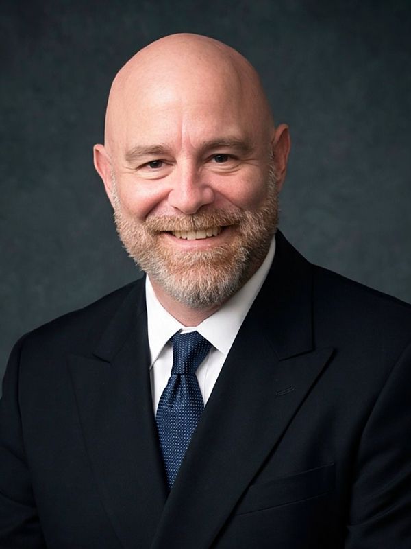Smiling bald man in a suit and tie.