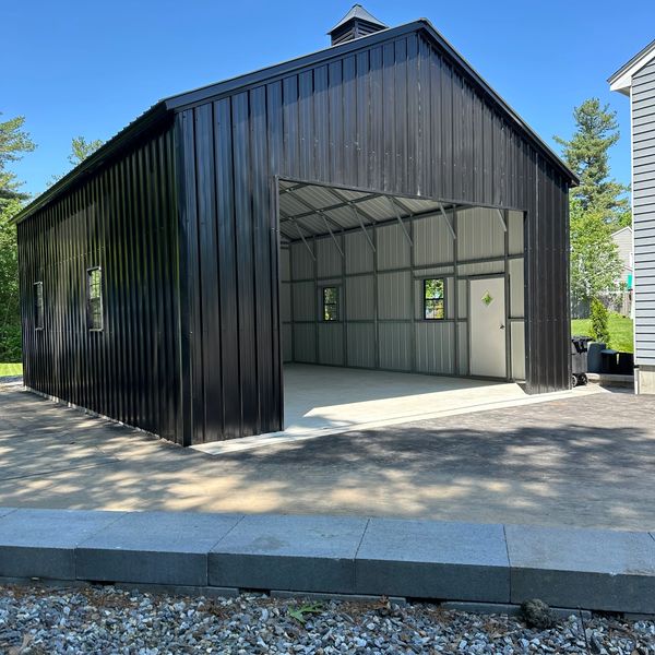 Black metal garage with open entrance and concrete floor.