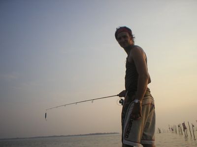 Young adult male with fishing rod in sunset