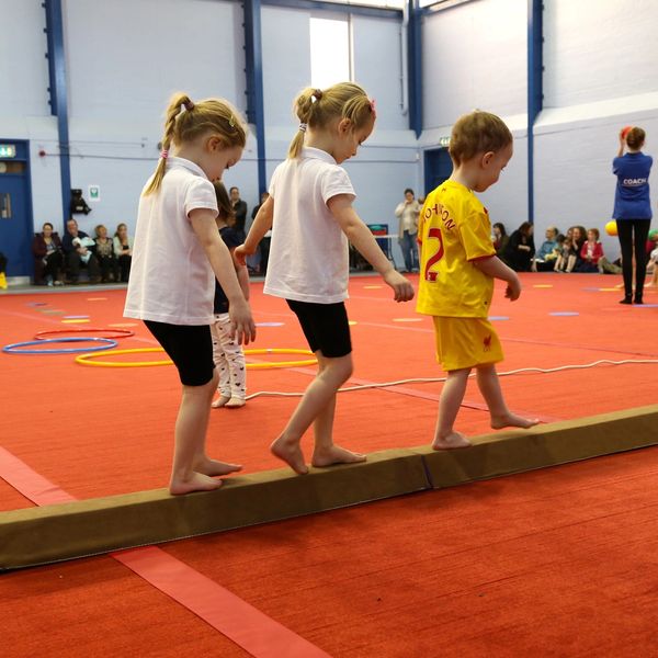 Three children walking on a beam