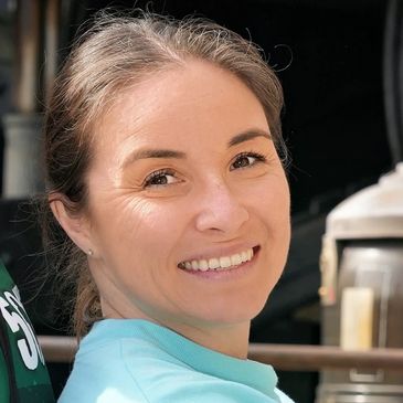 Smiling woman with light brown hair in a casual setting.