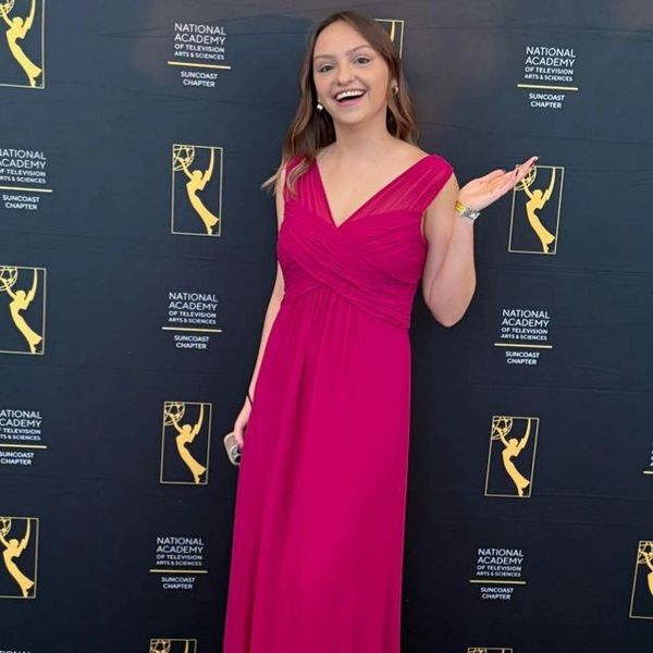 Mujer sonriente con vestido rosa en evento formal.