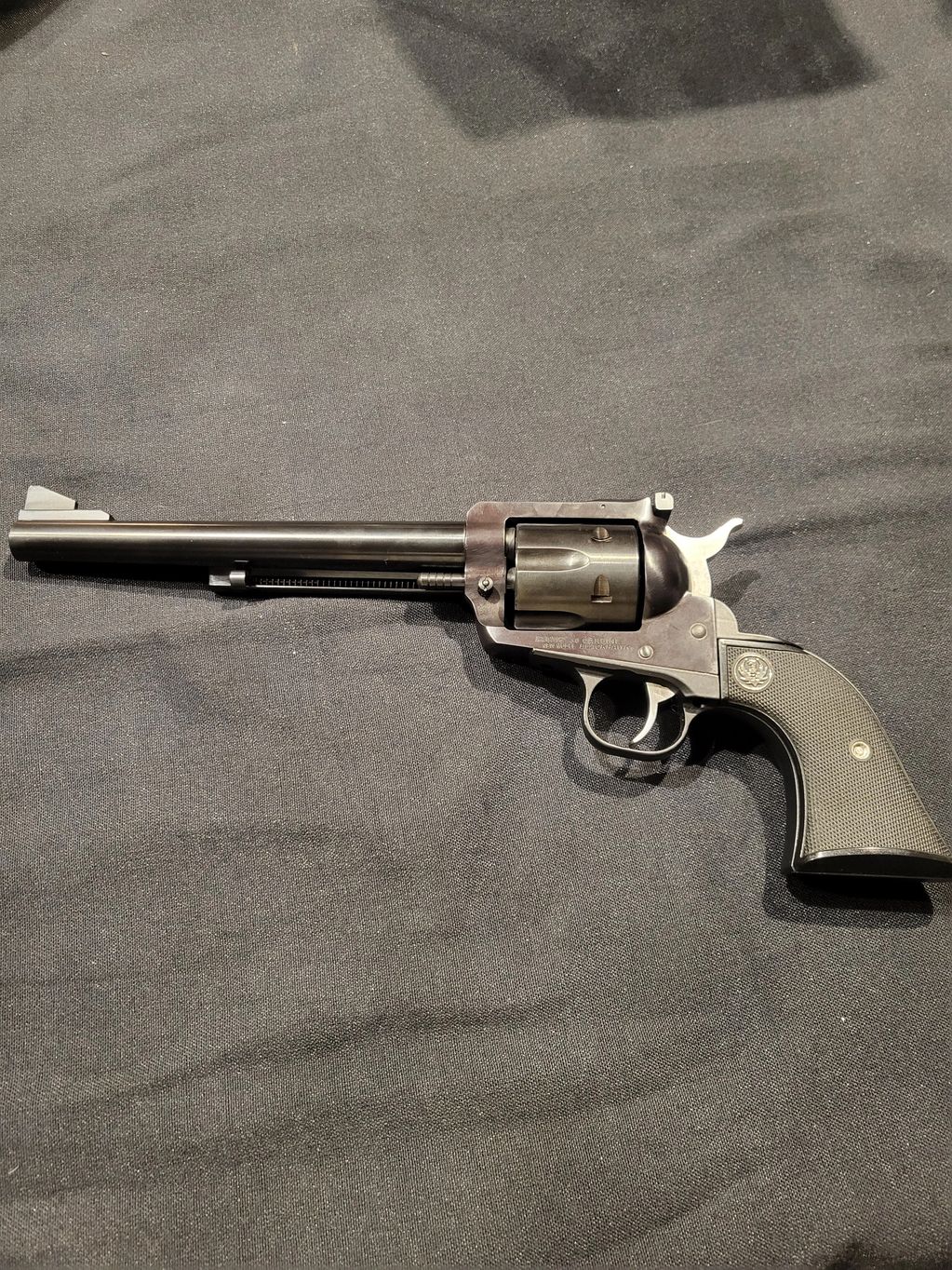 A detailed image of a classic revolver on a black fabric background.