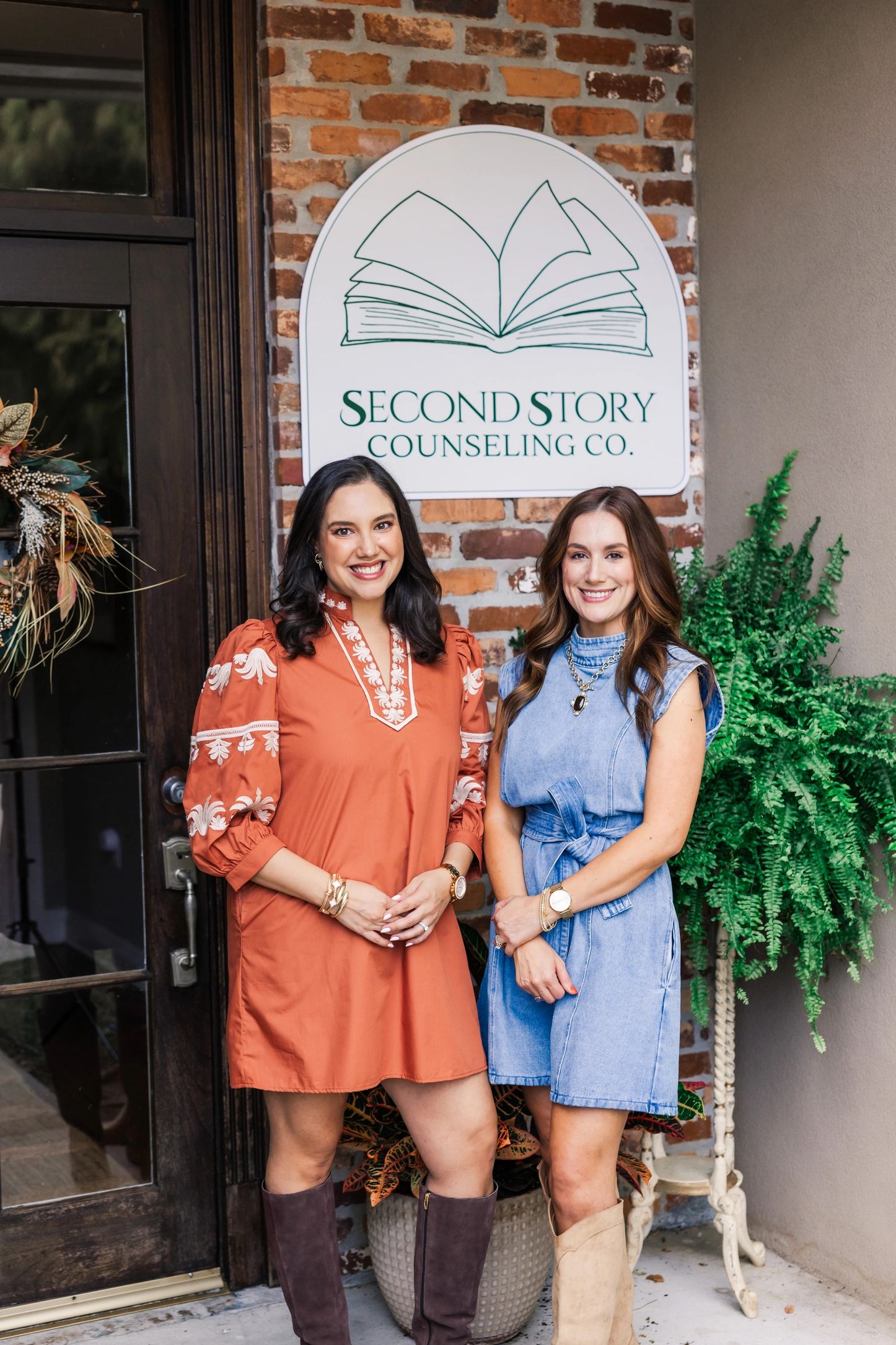 Two women smiling in front of Second Story Counseling Co. sign.