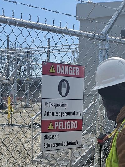 Bilingual No Trespassing sign on .063 aluminum, fence-mounted at a substation