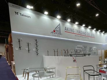Modern furniture displayed at the Aking Trading Co. Ltd booth in a large exhibition hall.
