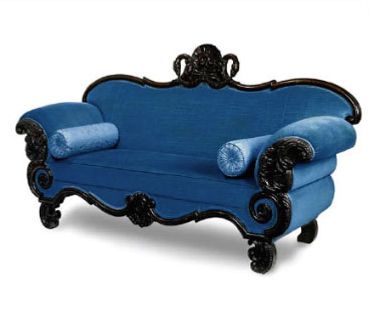 Ornate blue velvet couch with roll accent pillows and black lacquer trim.