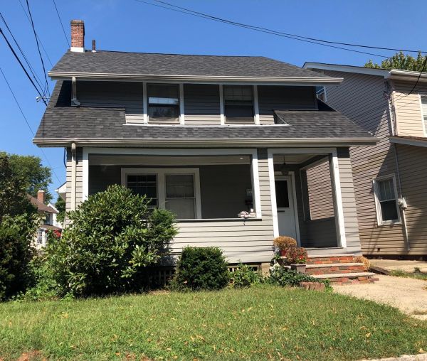 Gray two-story house with a front porch and green lawn.