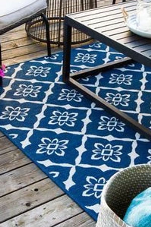 Blue and white floral patterned rug on wooden deck under a table.
