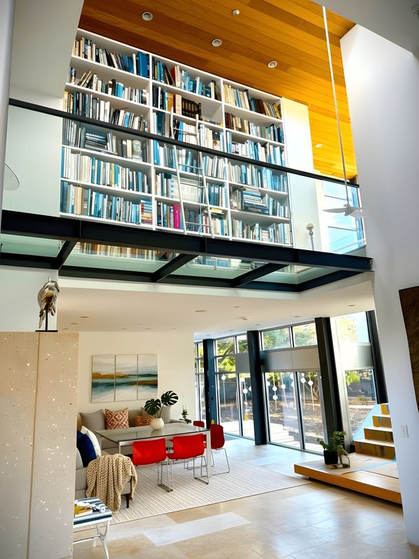 Modern living room with tall bookshelves and red chairs.