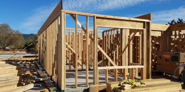 Wooden house frame under construction on a sunny day.