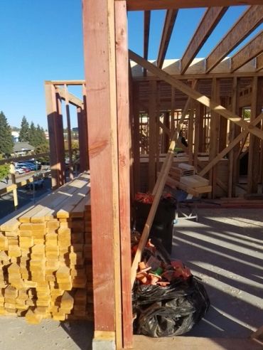 Wood framing and lumber at a construction site under clear skies.