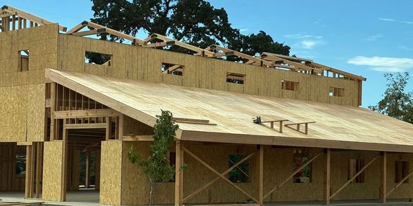 Wooden house construction in progress under clear sky.