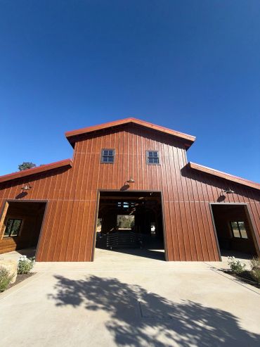 A tall red barn under a clear blue sky.