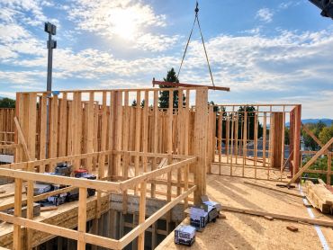 Wooden framing construction in progress under a bright sky.