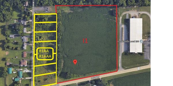 Aerial view of land parcels outlined in red and yellow near residential and industrial areas.