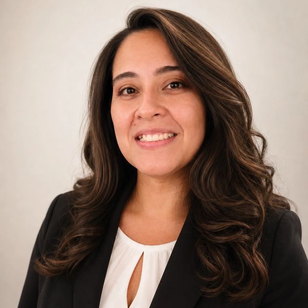 Professional woman with long wavy hair smiling in a formal portrait.