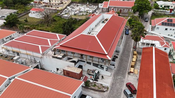 Aerial view of red-roofed buildings in a residential area with parked cars.