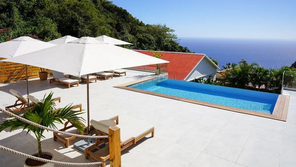 A serene poolside area with lounge chairs and umbrellas overlooking the ocean.