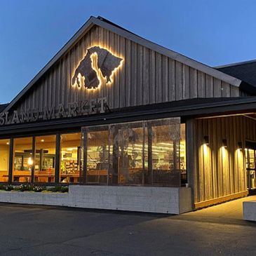 Evening view of a rustic market building with illuminated logo.