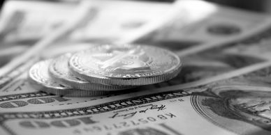 Close-up of coins stacked on US dollar bills in black and white.