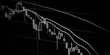 A declining candlestick chart with moving averages on a black background.