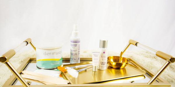 A golden tray with skincare and waxing tools arranged neatly on a fluffy surface.
