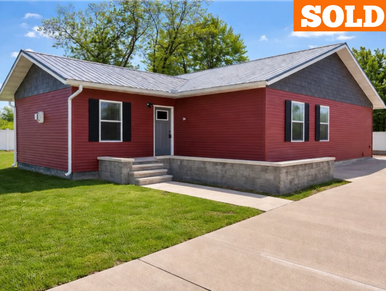 New red house with a small concrete porch and green lawn.
