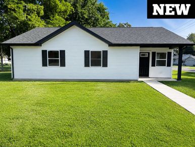 Newly built white house with black shutters and a green lawn.