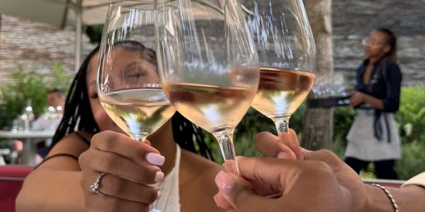 Three people clinking glasses of rosé wine in a cheerful toast.