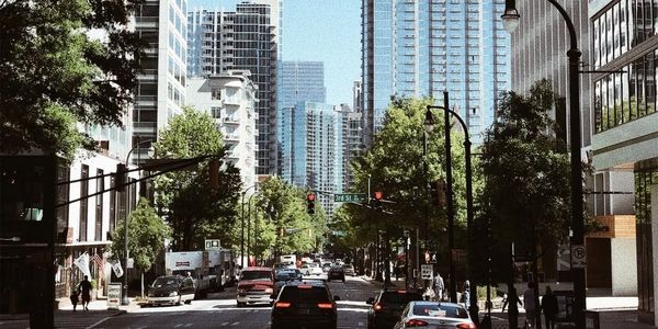 Busy urban street with cars and tall buildings under a clear sky.