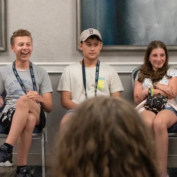 Teens engaged in a group activity, sharing laughter and attentiveness indoors.