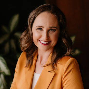 Woman in orange blazer smiling.