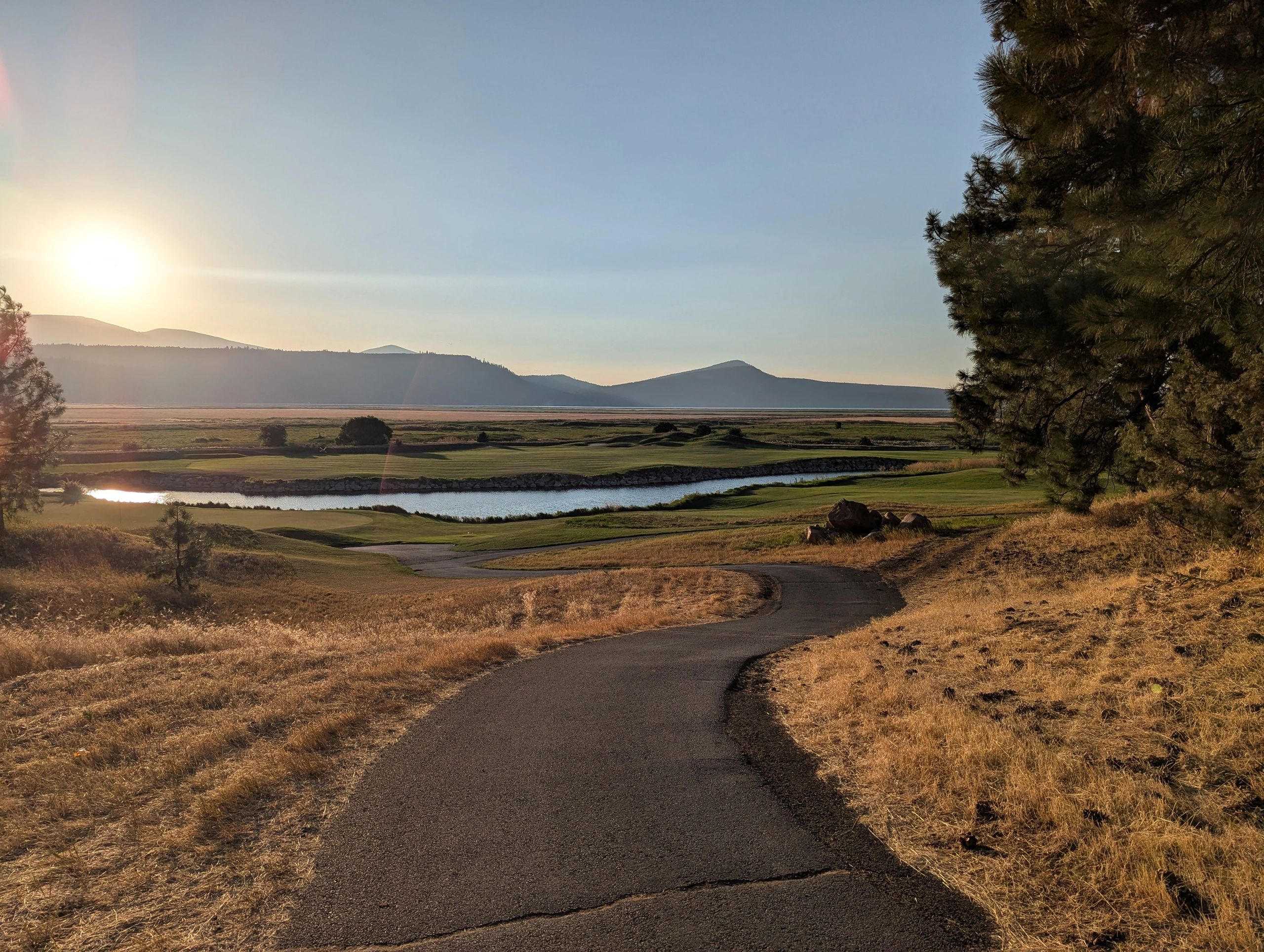 Sunset over a golf course with mountains in the distance.