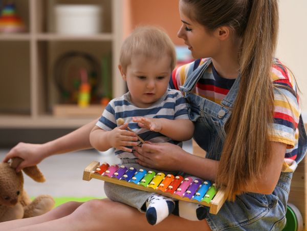 Child playing xylophone with adult guidance.