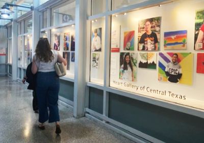 Woman walking past art display at Heart Gallery of Central Texas.