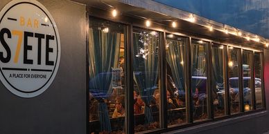 Exterior of Bar Stete at night with patrons inside.