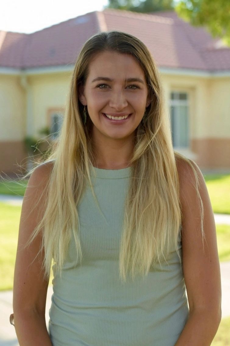 Smiling woman with long blonde hair outdoors.