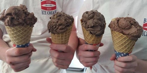 Four chocolate flavored ice creams scooped into waffle cones.