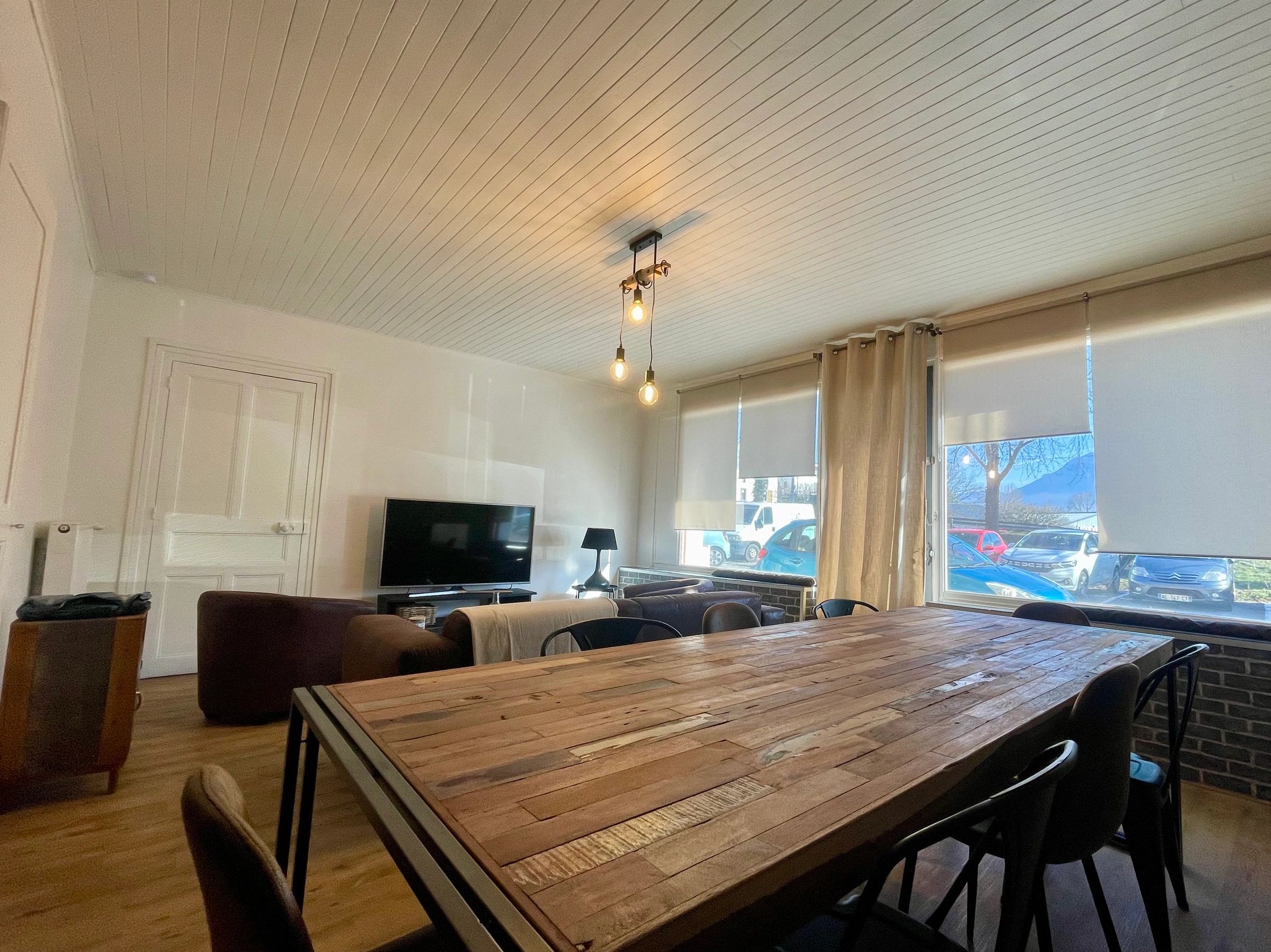 Cozy living room with wooden table and hanging light bulbs.