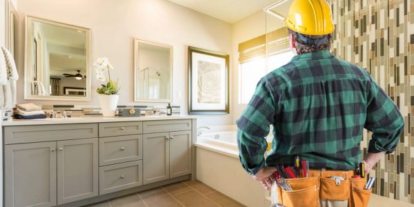 Construction worker inspecting a modern bathroom with tools.